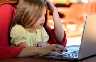 Mother working at a laptop with her child